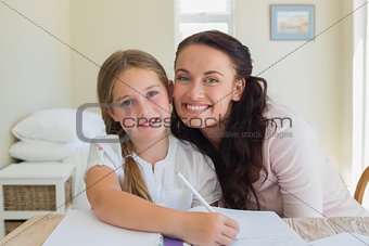 Loving mother with daughter studying at table