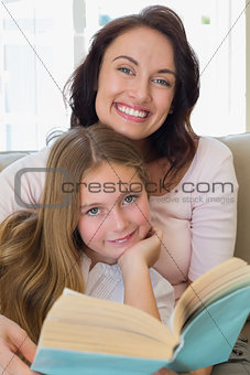 Woman and daughter with book at home
