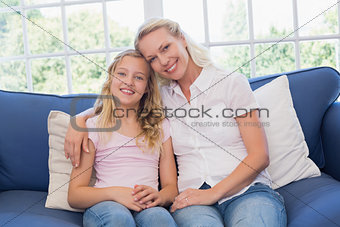 Mother and daughter sitting on sofa