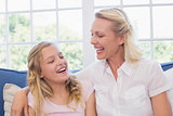 Mother and daughter laughing on sofa