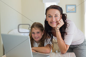 Mother and daughter using laptop at home