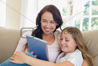Mother and daughter using digital tablet in house