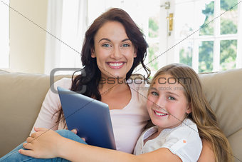 Mother and daughter with digital tablet on sofa