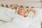 Woman stretching while waking up in bed