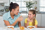 Mother and daughter having muffin at table