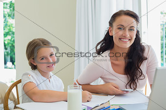 Happy mother and daughter working at table