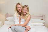 Mother and daughter sitting on bed