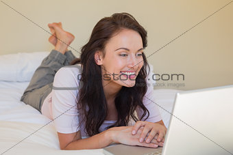 Woman using laptop while lying in bed