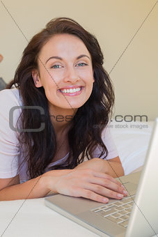 Relaxed woman using laptop in bed at home