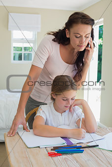 Woman on call looking at daughter studying at table