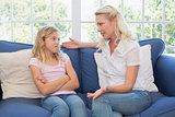 Woman explaining little girl on sofa