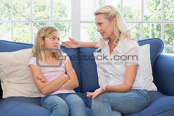 Woman explaining little girl on sofa