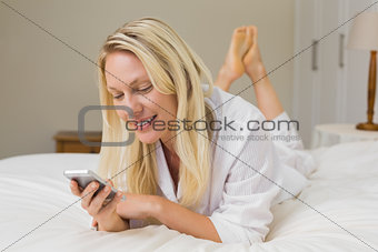 Woman reading text message on mobile phone in bed