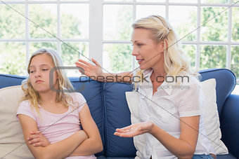 Mother scolding daughter on sofa
