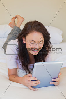 Woman using tablet PC while lying in bed