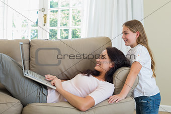 Woman using laptop while daughter looking at it