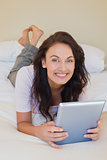 Woman holding digital tablet while lying in bed
