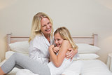 Woman tickling daughter in bed