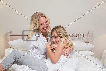 Woman tickling daughter in bed