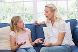 Angry mother scolding daughter on sofa