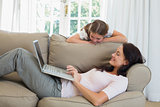 Mother using laptop while daughter looking at it