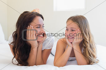 Mother and daughter lying together in bed