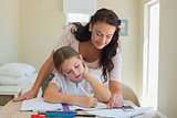 Mother assisting little daughter in homework