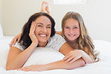 Woman and daughter lying together in bed