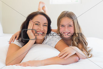 Woman and daughter lying together in bed