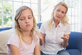 Angry mother explaining daughter on sofa