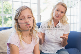 Angry mother explaining daughter on sofa