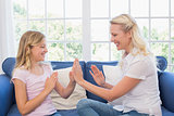 Mother and daughter playing clapping game on sofa