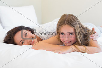 Cute daughter with mother relaxing in bed