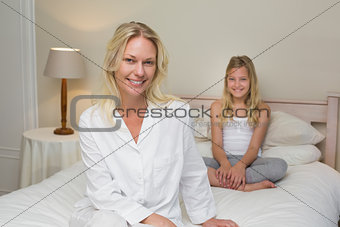 Woman with daughter sitting on bed