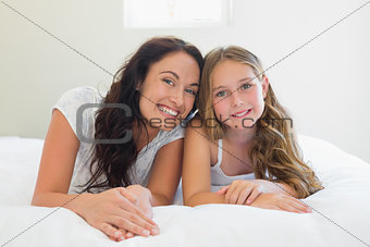 Mother with cute daughter lying in bed