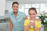 Girl having milk while mother standing by in kitchen