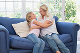 Mother and daughter embracing on sofa