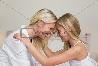Mother and daughter with head to head in bedroom