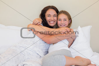 Mother and daughter embracing in bed