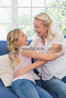 Mother embracing daughter on sofa