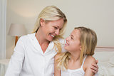 Mother and daughter looking at each other in bedroom