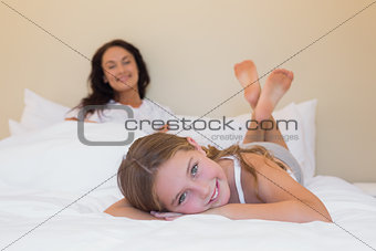 Girl lying in bed with mother in background