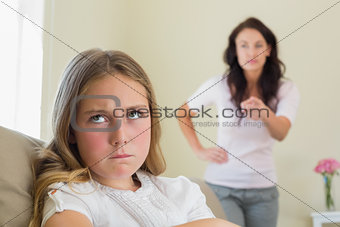 Angry girl with mother scolding her in background