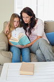 Girl and mother reading novel on sofa