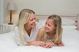Woman looking at daughter while lying in bed