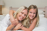 Loving mother and daughter lying in bed