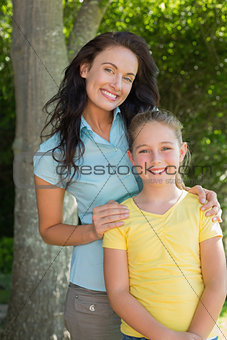 Happy mother and daughter standing in park