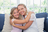 Happy mother and daughter embracing on sofa