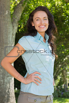 Confident woman with hands on waist in park