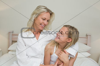Mother and daughter looking at each other in bed